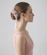 Ballerina with a floral hair accessory and pink dress on a plain background 