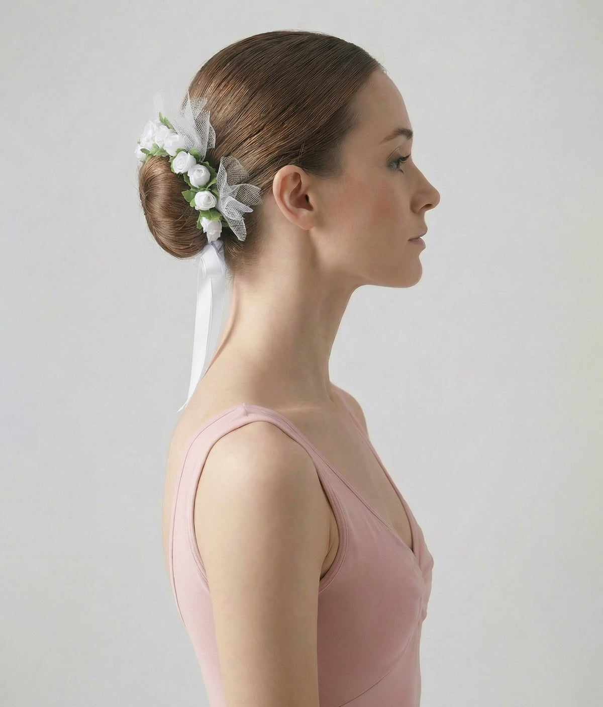Ballerina with a floral hair accessory and pink dress on a plain background 