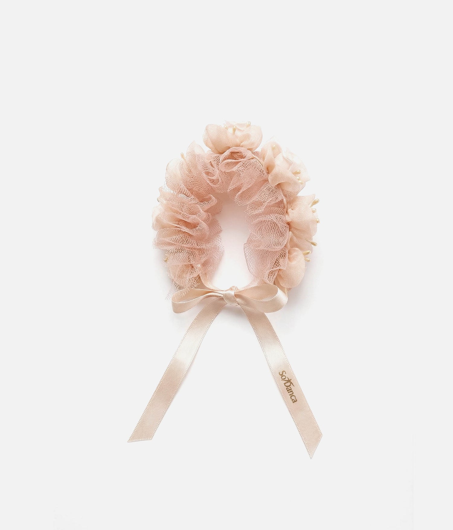 Woman wearing a pink floral hair accessory with a plain background 