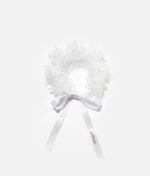 Woman wearing a white floral hair accessory with a plain background 