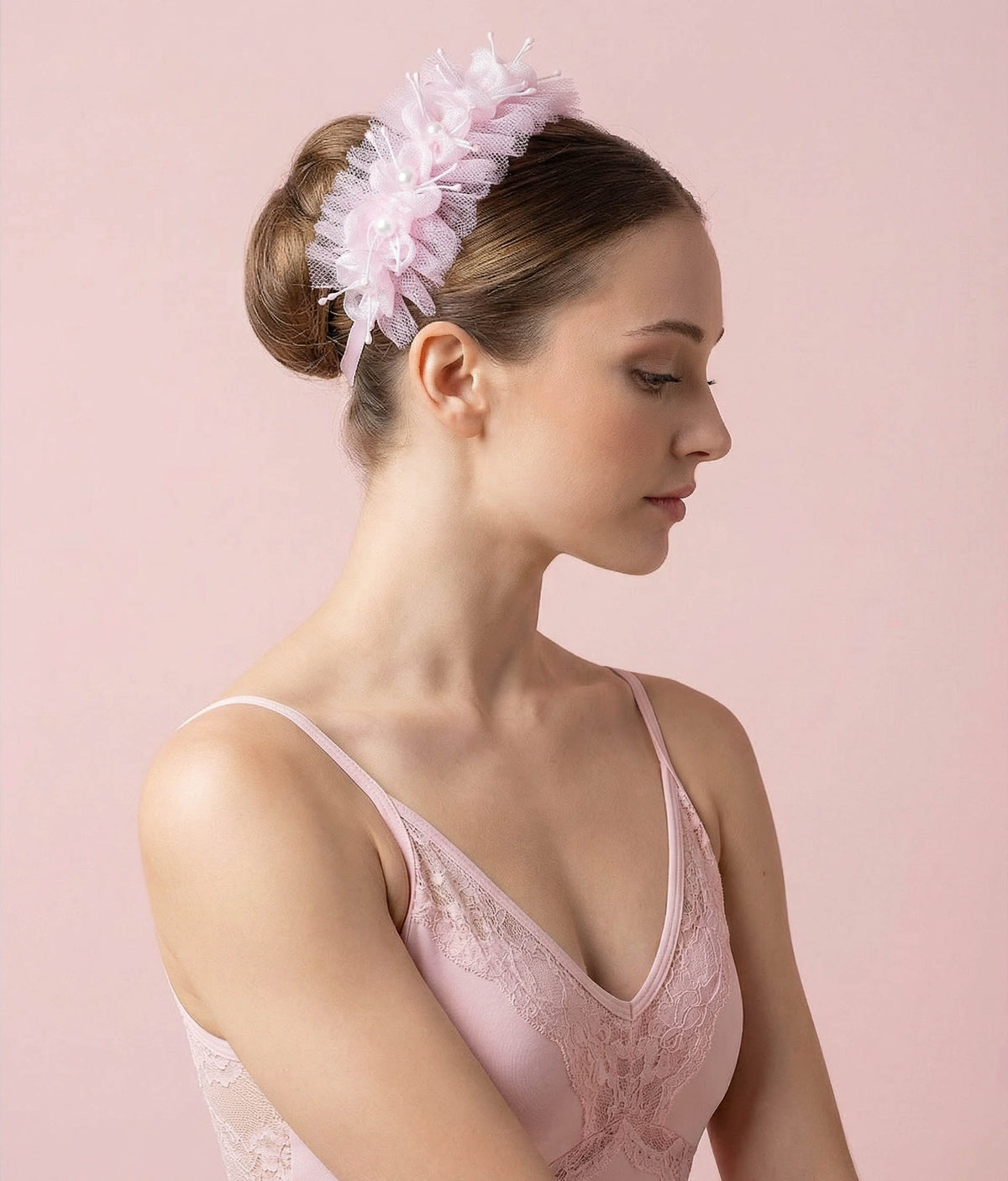 Woman wearing a pink floral hair accessory with a plain background 