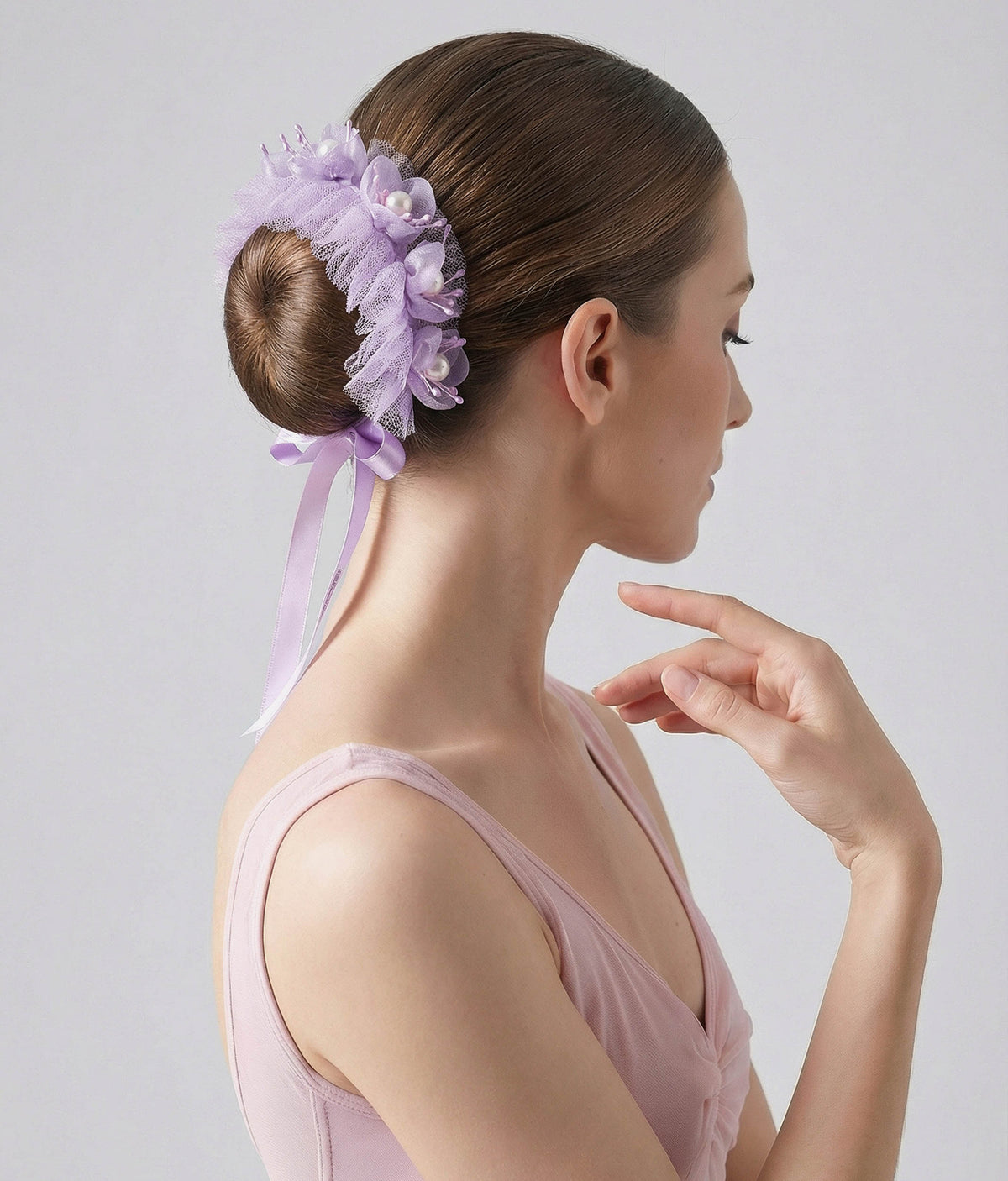 Woman wearing a lilac floral hair accessory with a plain background 