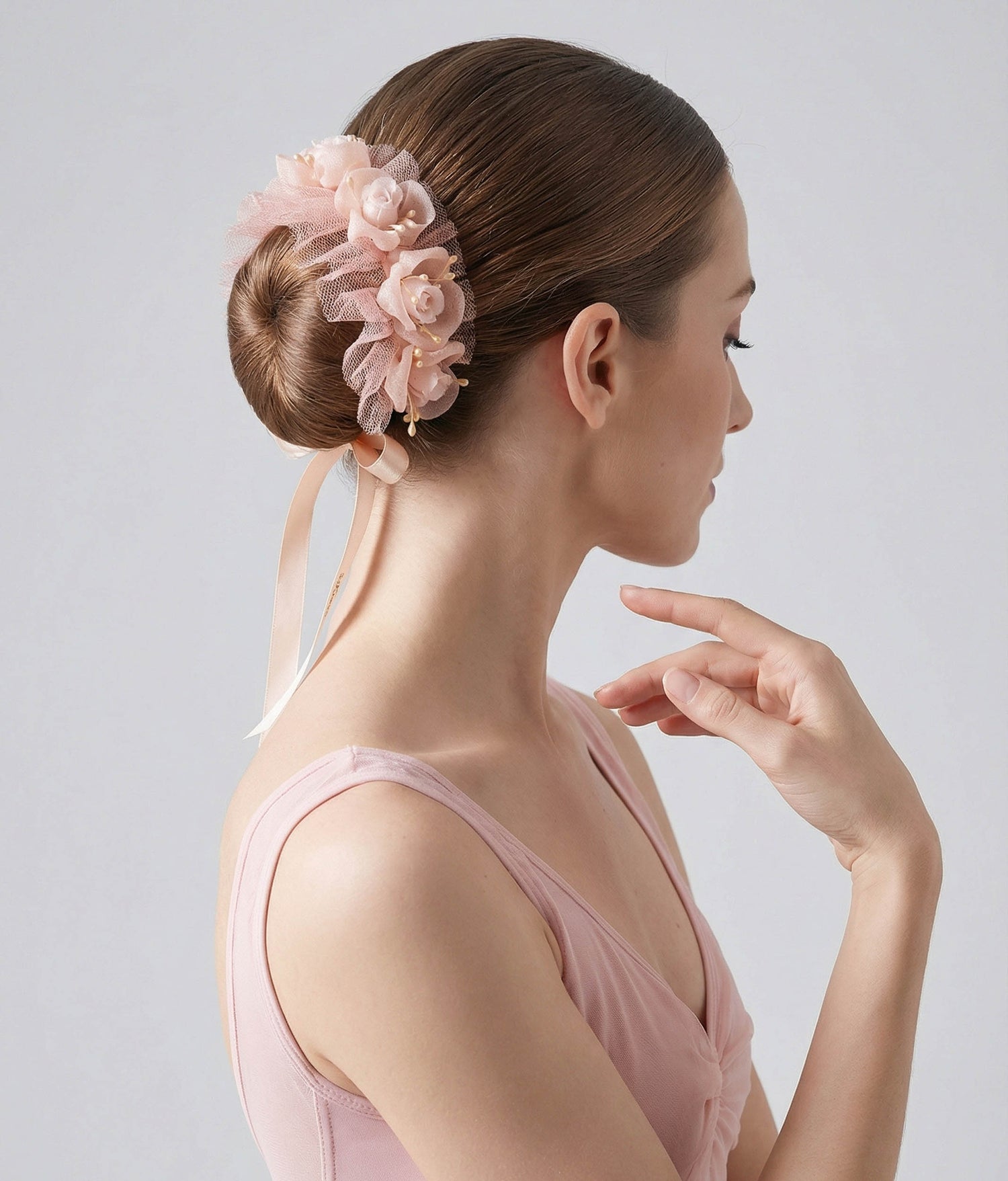 Woman wearing a pink floral hair accessory with a plain background 