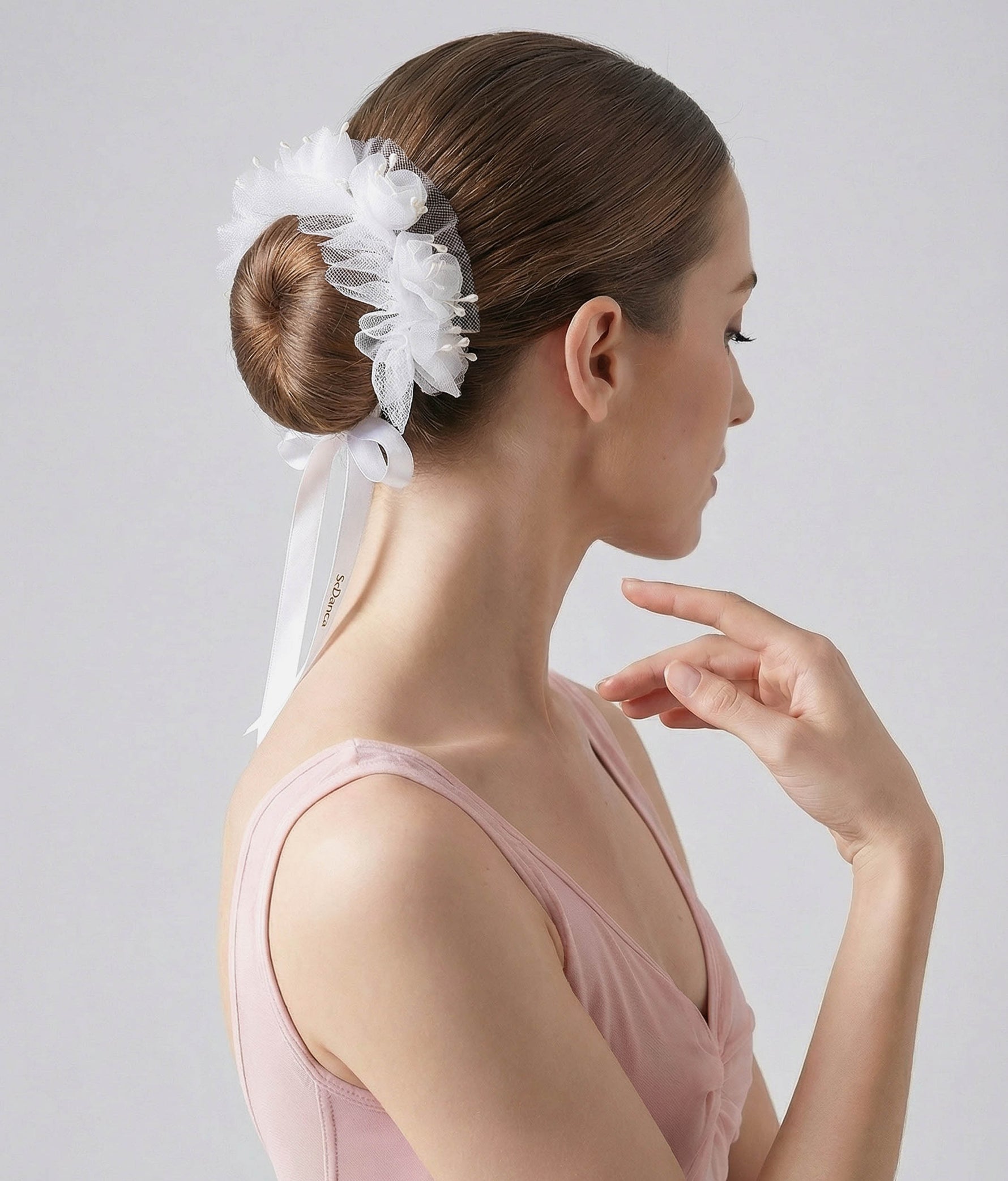 Woman wearing a white floral hair accessory with a plain background 