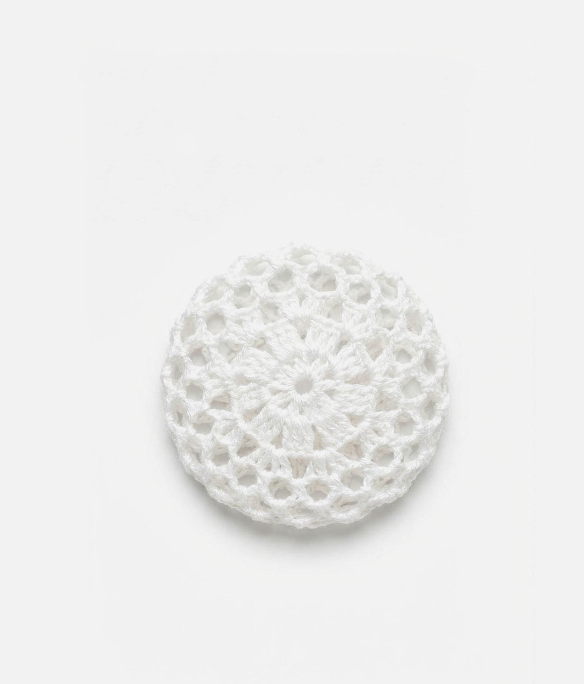 Woman wearing a pink top with a decorative hair accessory on a plain background 