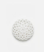 Woman wearing a pink top with a decorative hair accessory on a plain background 