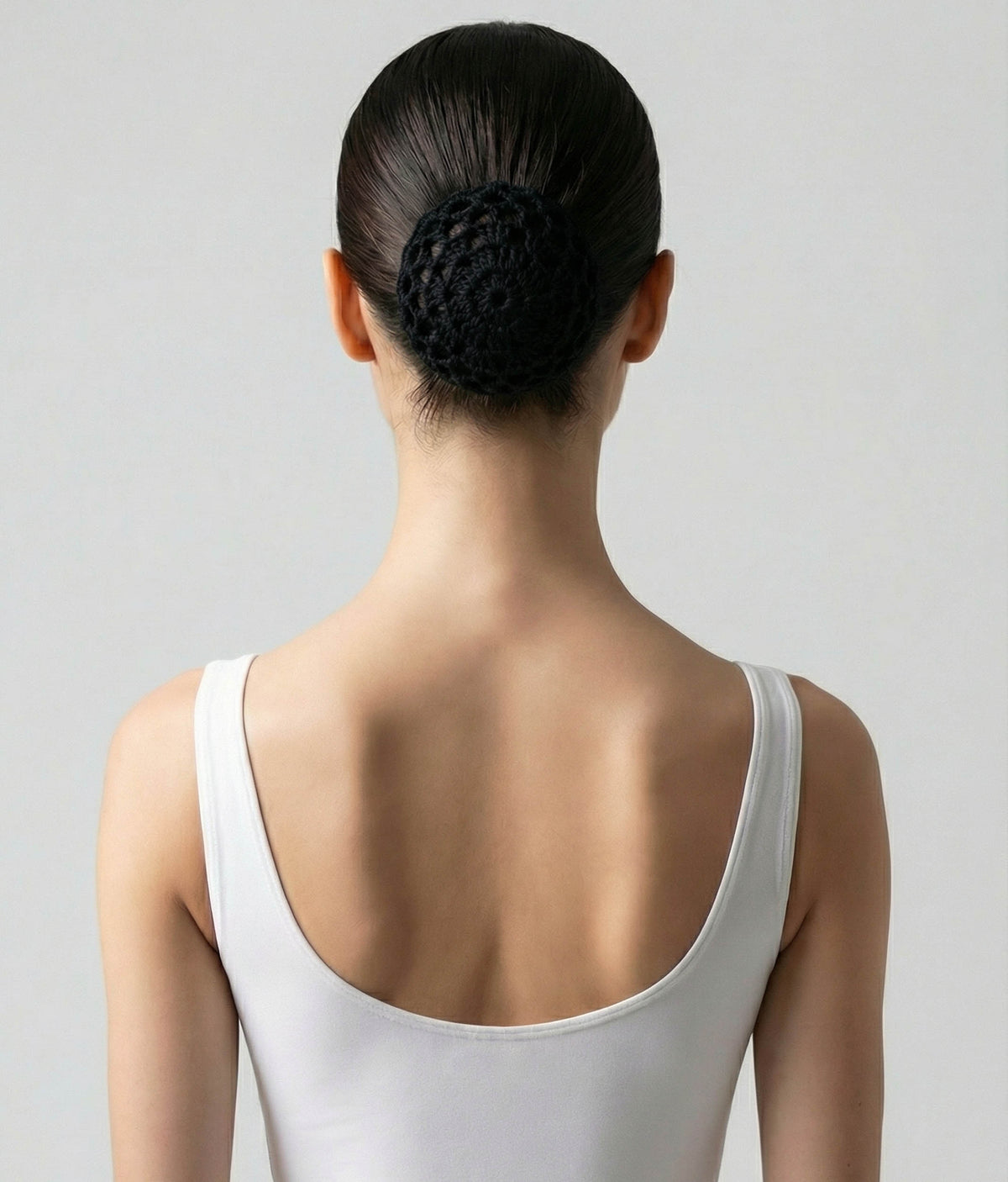 Woman wearing a pink top with a decorative hair accessory on a plain background 