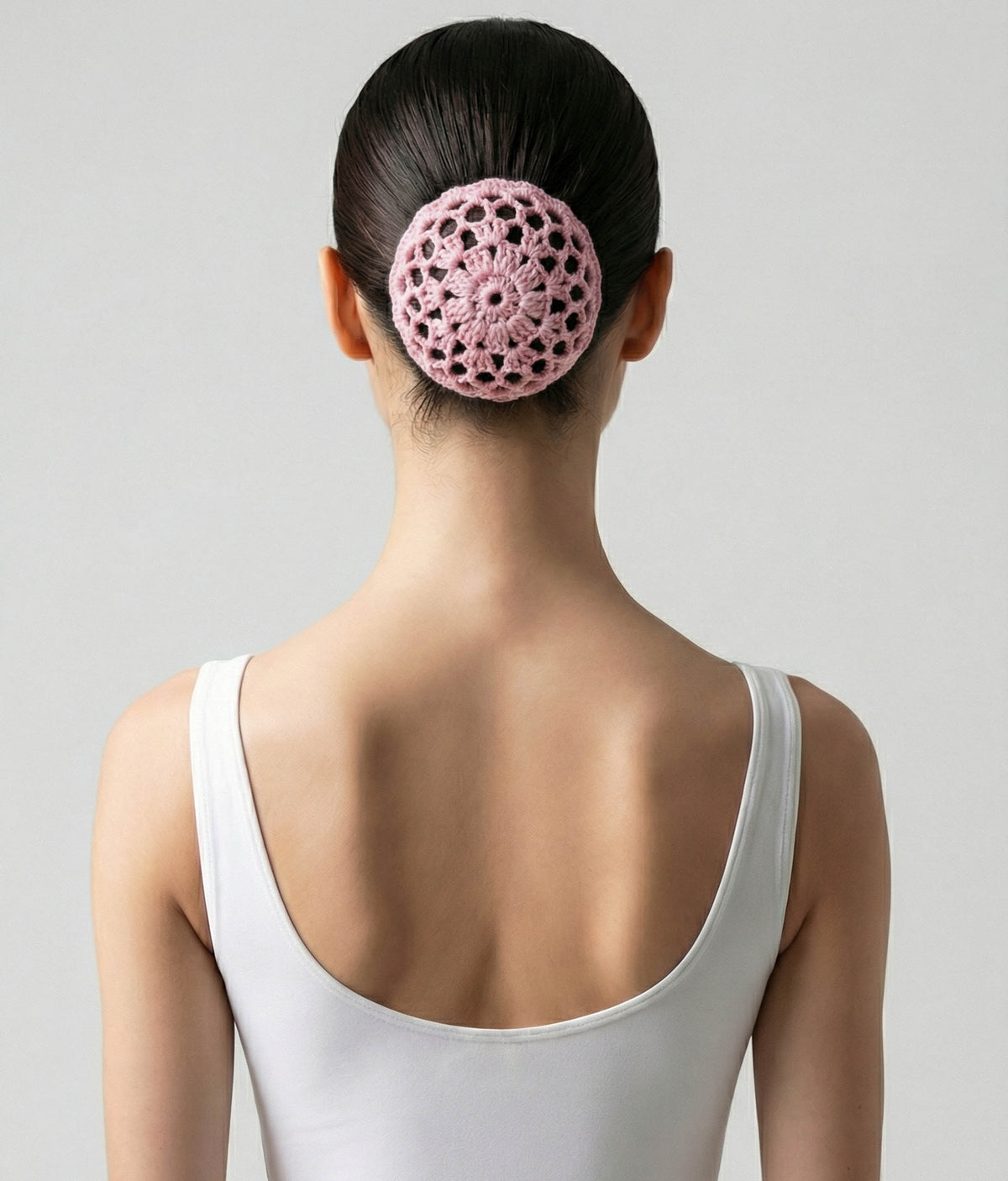 Woman wearing a pink top with a decorative hair accessory on a plain background 