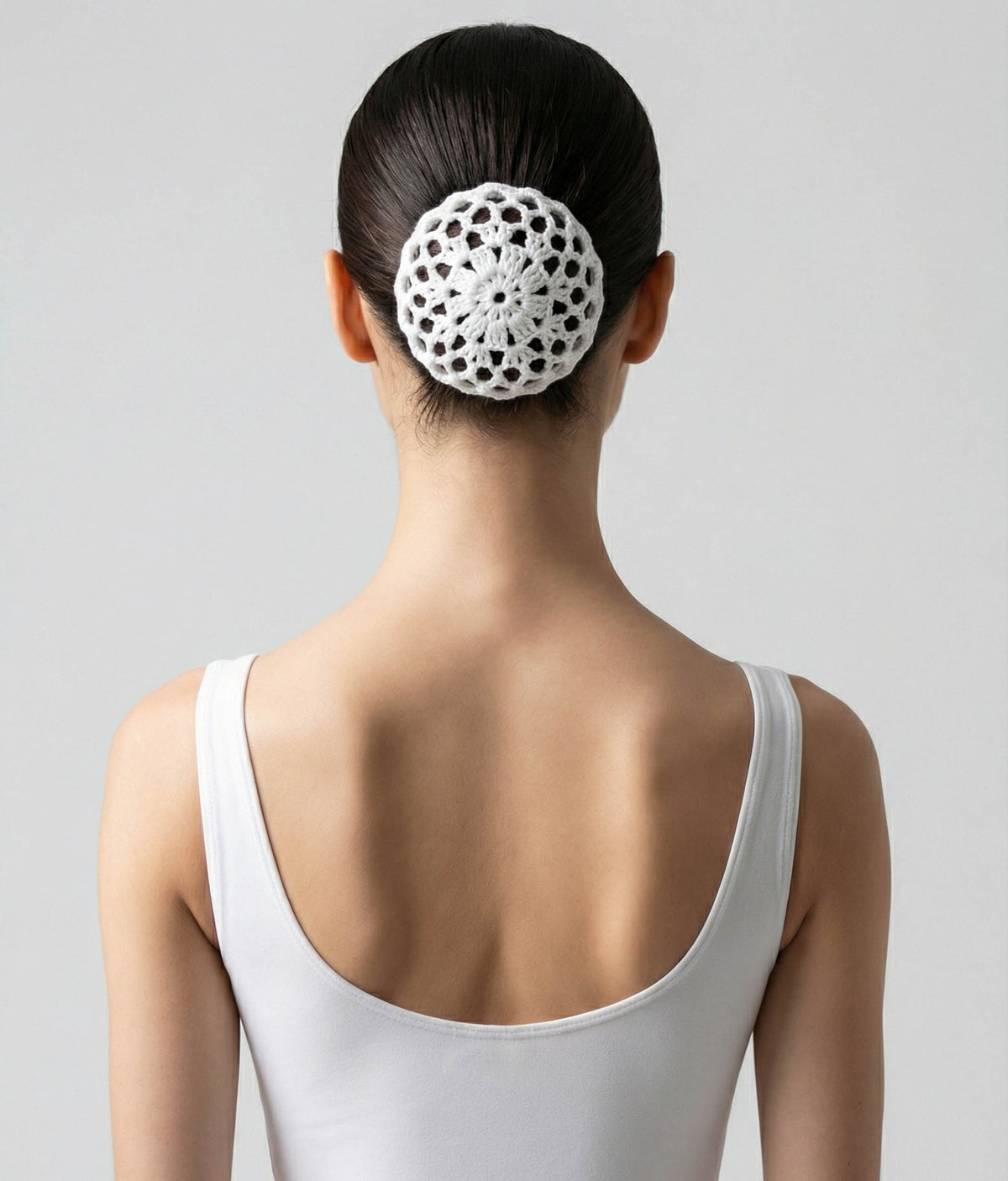 Woman wearing a pink top with a decorative hair accessory on a plain background 