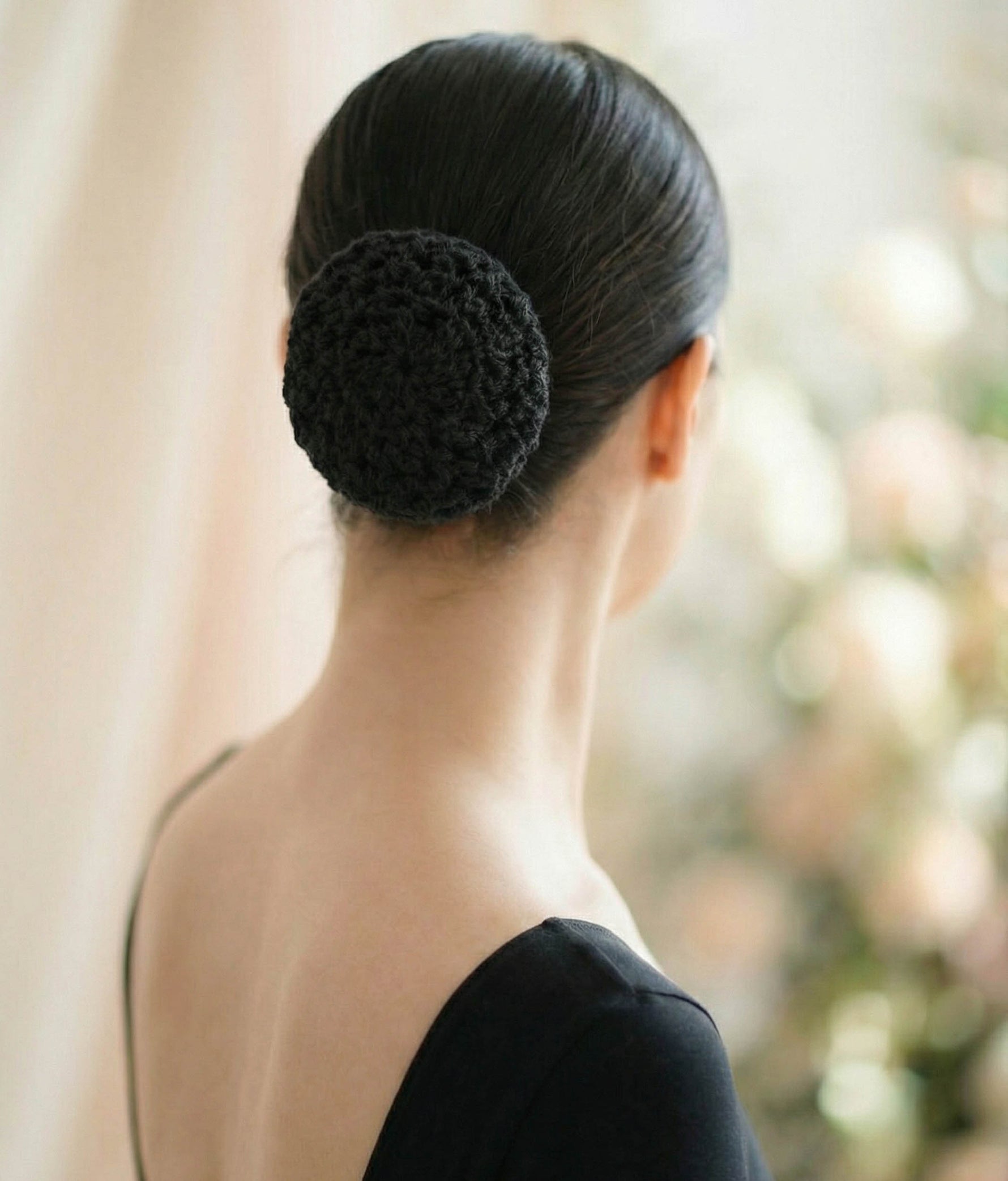 Woman wearing a pink top with a decorative hair accessory on a plain background 