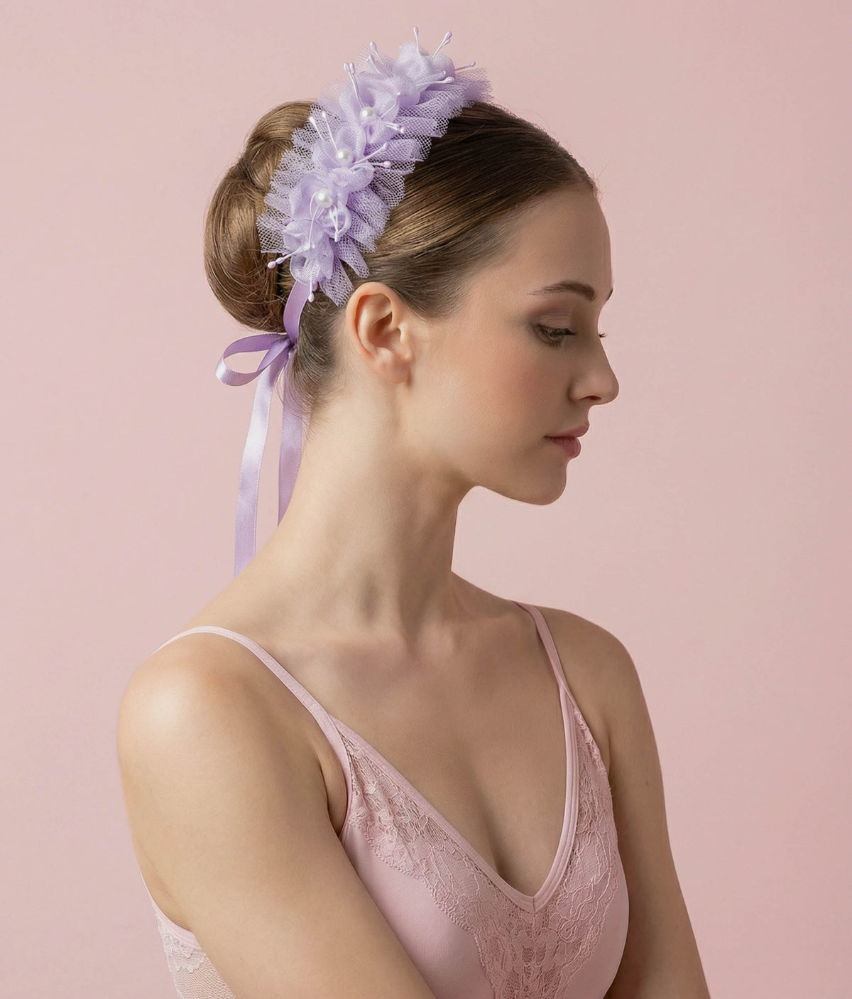 Woman wearing a lilac floral hair accessory with a plain background 