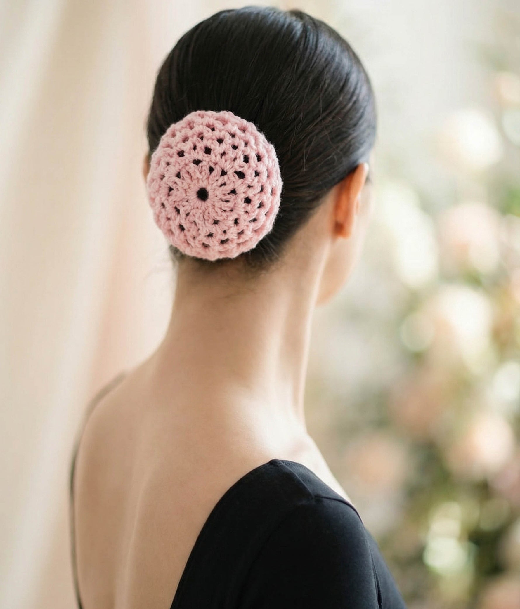 Woman wearing a pink top with a decorative hair accessory on a plain background 