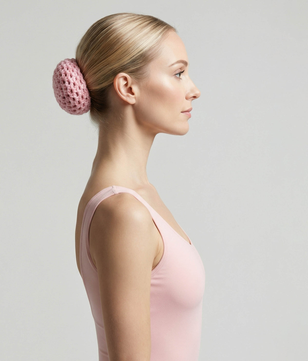 Woman wearing a pink top with a decorative hair accessory on a plain background 